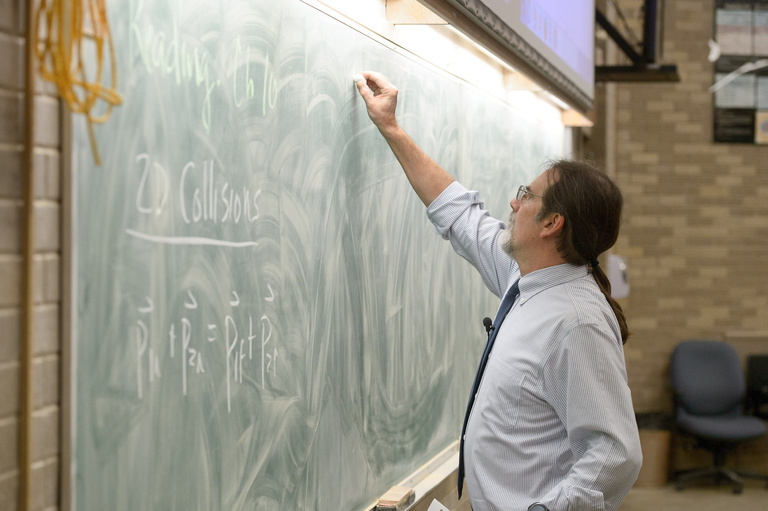 Kletzing writing on a blackboard in class